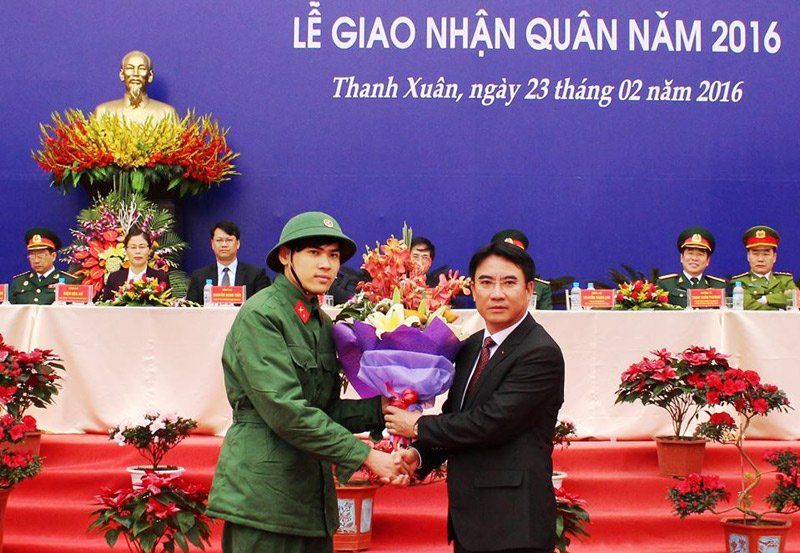 Chủ tịch UBND quận Thanh Xuân Nguyễn Xuân Lưu tặng hoa cho tân binh Ngô Quang Huy tại lễ giao, nhận quân. (Ảnh: Hồng Thái)