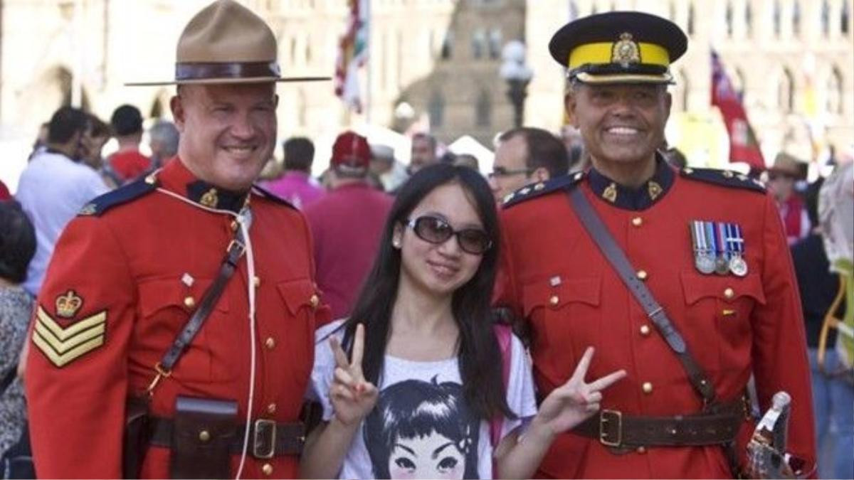 Cảnh vệ hoàng gia thân thiện chụp ảnh cùng du khách trong "Ngày Canada". Royal Canadian Mounted Police celebrating Canada Day. (Credit: George Rose/Getty)